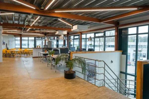 Moderne kantoorruimte aan de Johan van Hasseltweg met open werkplekken, gele eetkamerstoelen en grote ramen voor natuurlijk licht.